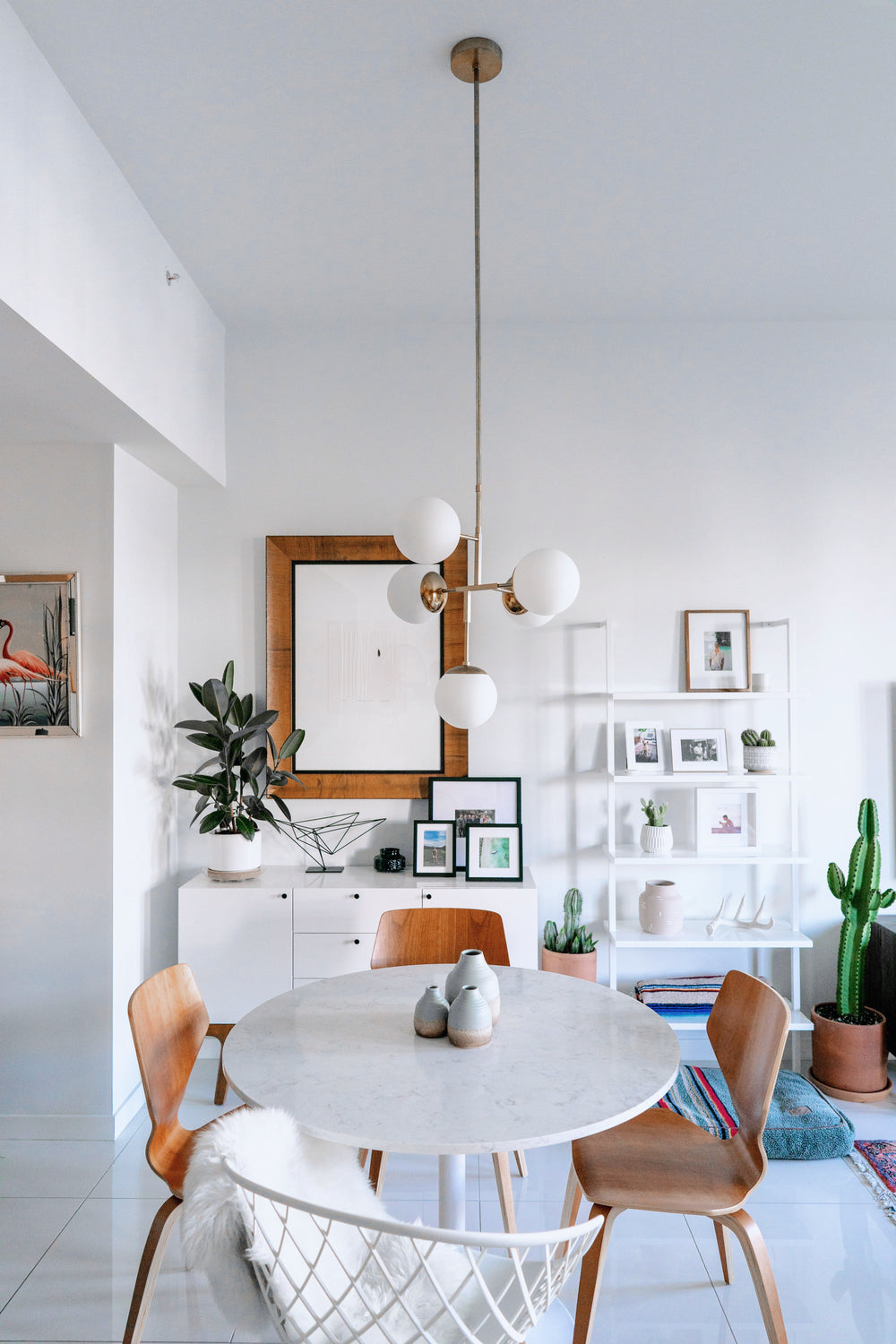 Modern dining room with marble table, wooden chairs, and decorative elements.